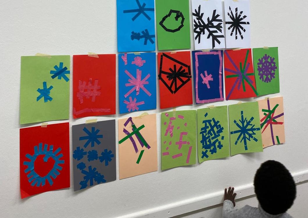 Kita-Kinder haben Schneeflocken aus Klebeband in verschiedenen Farben gestaltet.