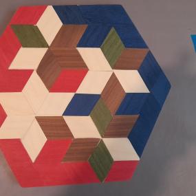 Verschiedene Furnier-Quadrate in Rot, Blau und Braun wurden zu Sternen zusammengepresst. 