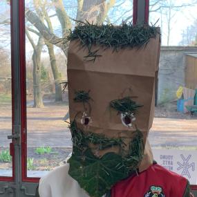 Ein Junge hat seiner Maske mit Efeu einen Bart gemacht. 
