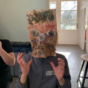 Ein Junge hat seine Maske Laub, Gras und Klopapierrollen verziert. 