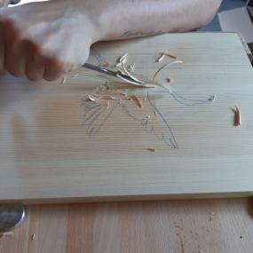 Eine neue Schnitzabeit wird begonnen. Es sind erste Kerben zu sehen. Das Schnitzeisen bohrt sich in das Holz. 