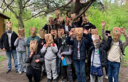 Eine Klasse trägt die fertigen Masken und macht ein Gruppenbild vor einem Baum. 